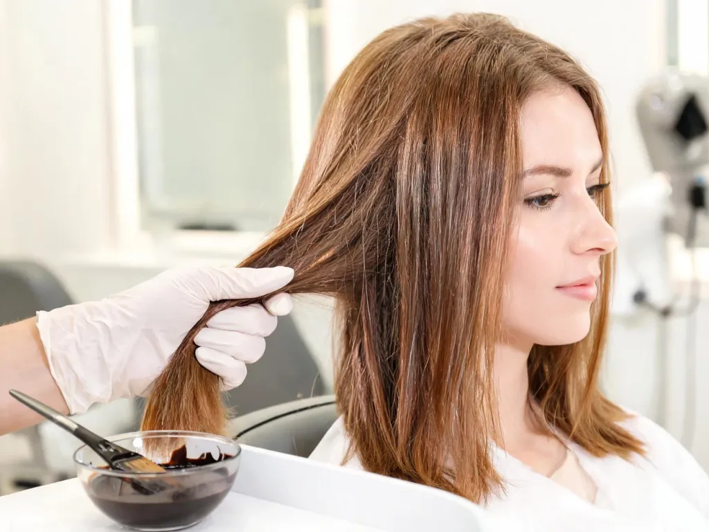 Stylista delikatnie trzyma zdrowe, lśniące włosy klientki, przygotowując szampon koloryzujący w nowoczesnym salonie.